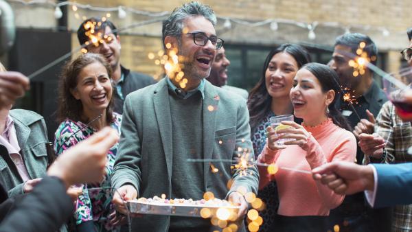 Group of people celebrating with cake and sparklers