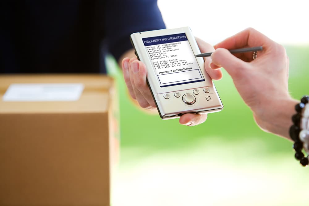 Someone using a digital signing pad to accept a package delivery