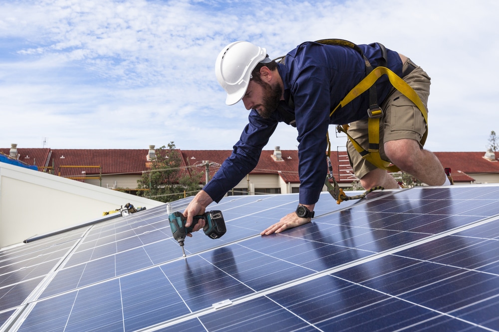 man fitting solar panels to roof