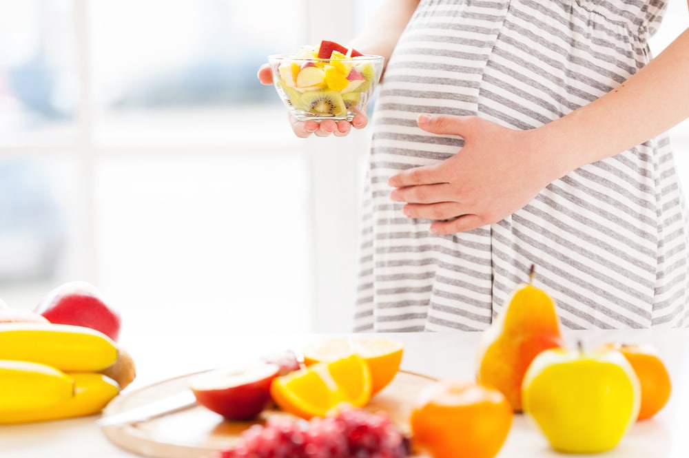 Prgnant woman holding bowl of fruit