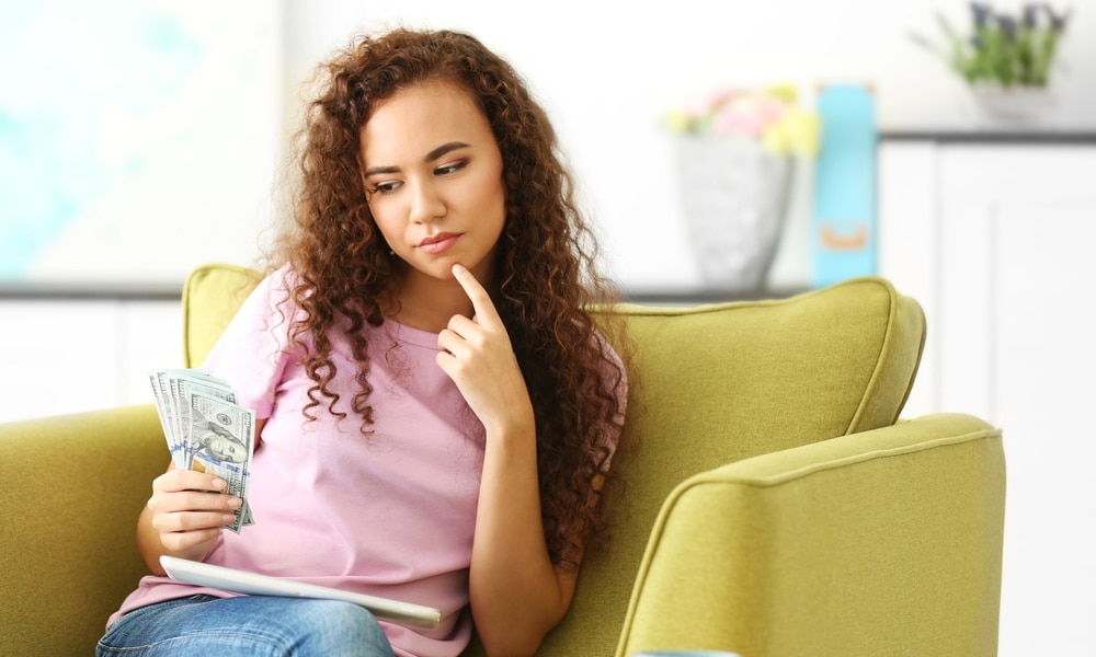 Woman looking at cash thoughtfully