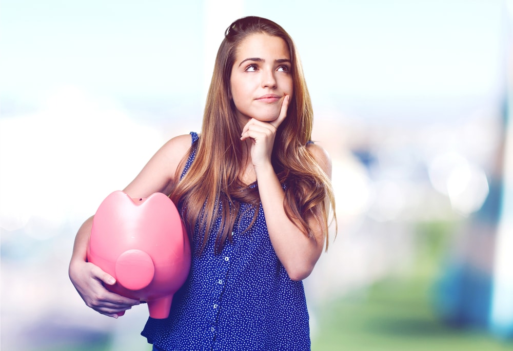 Woman holding piggy bank and looking thoughtful